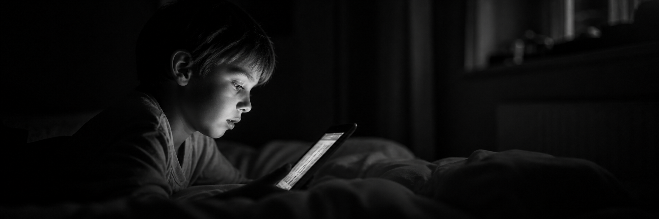 Enfant seul dans le noir face à un écran